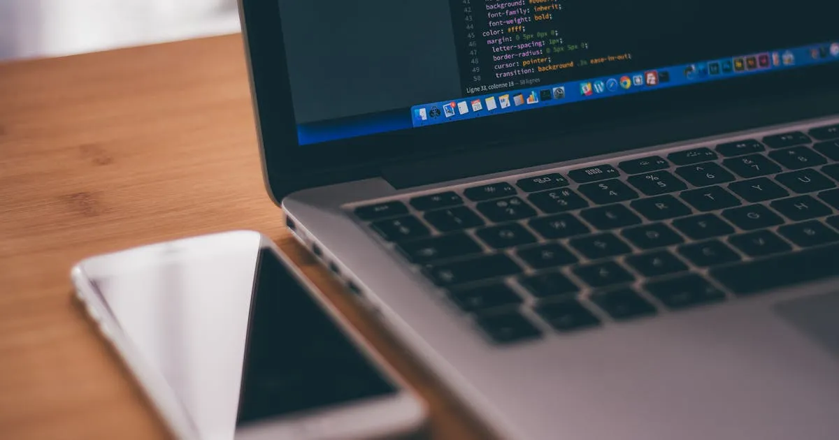 Laptop with code and smartphone — mobile developer workspace