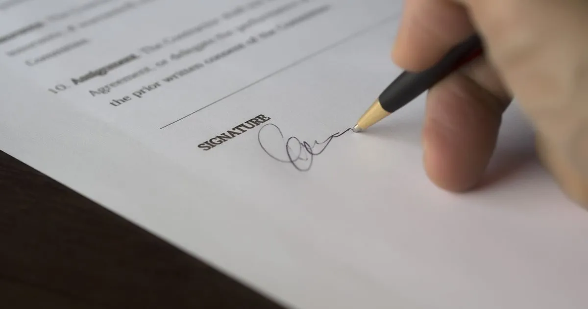 Hand signing a fixed-term employment contract with a pen