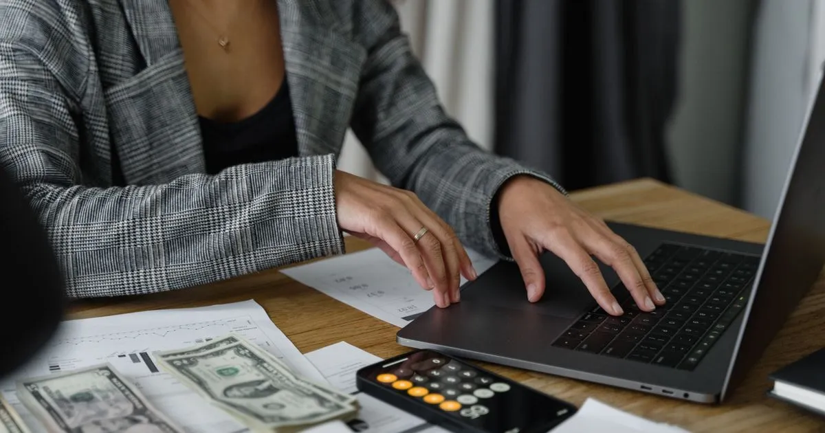 Businesswoman calculating gross salary with cash and calculator